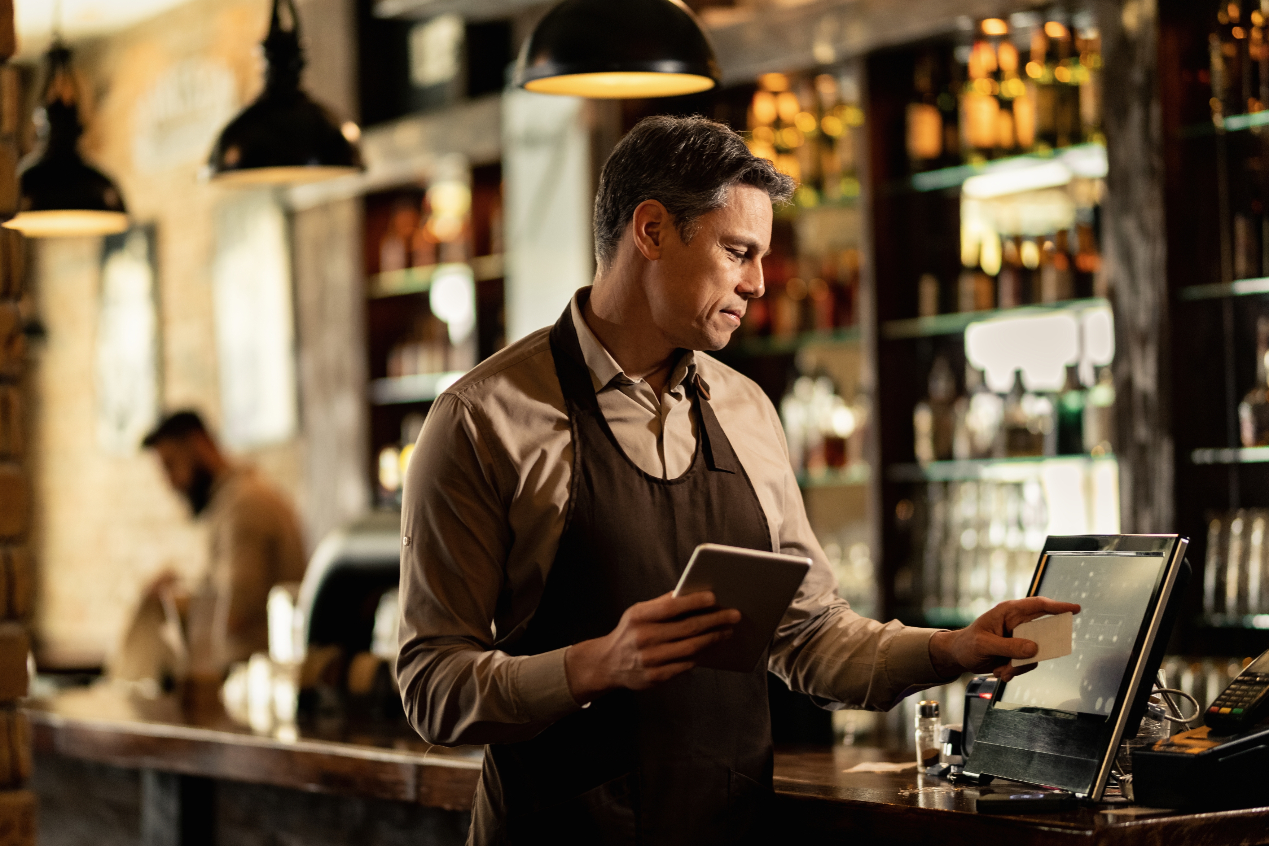 A woman with shoulder length hair and wearing an apron stands at counter, entering information into a point-of-sale terminal. Text next to the image reads, “5G Business Internet plans. High-speed internet and a network you can depend on.”