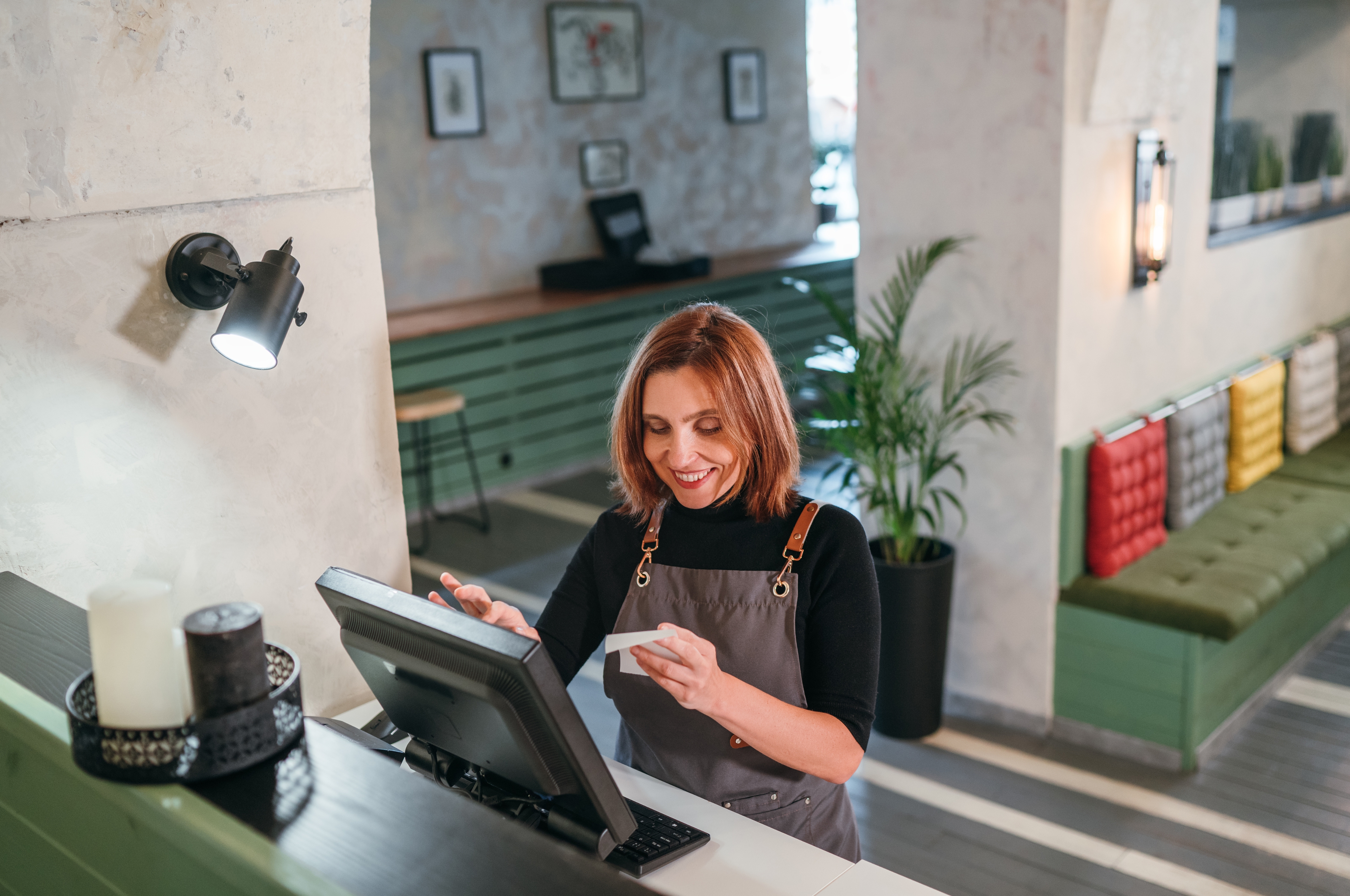 A woman with shoulder length hair and wearing an apron stands at counter, entering information into a point-of-sale terminal. Text next to the image reads, “5G Business Internet plans. High-speed internet and a network you can depend on.”