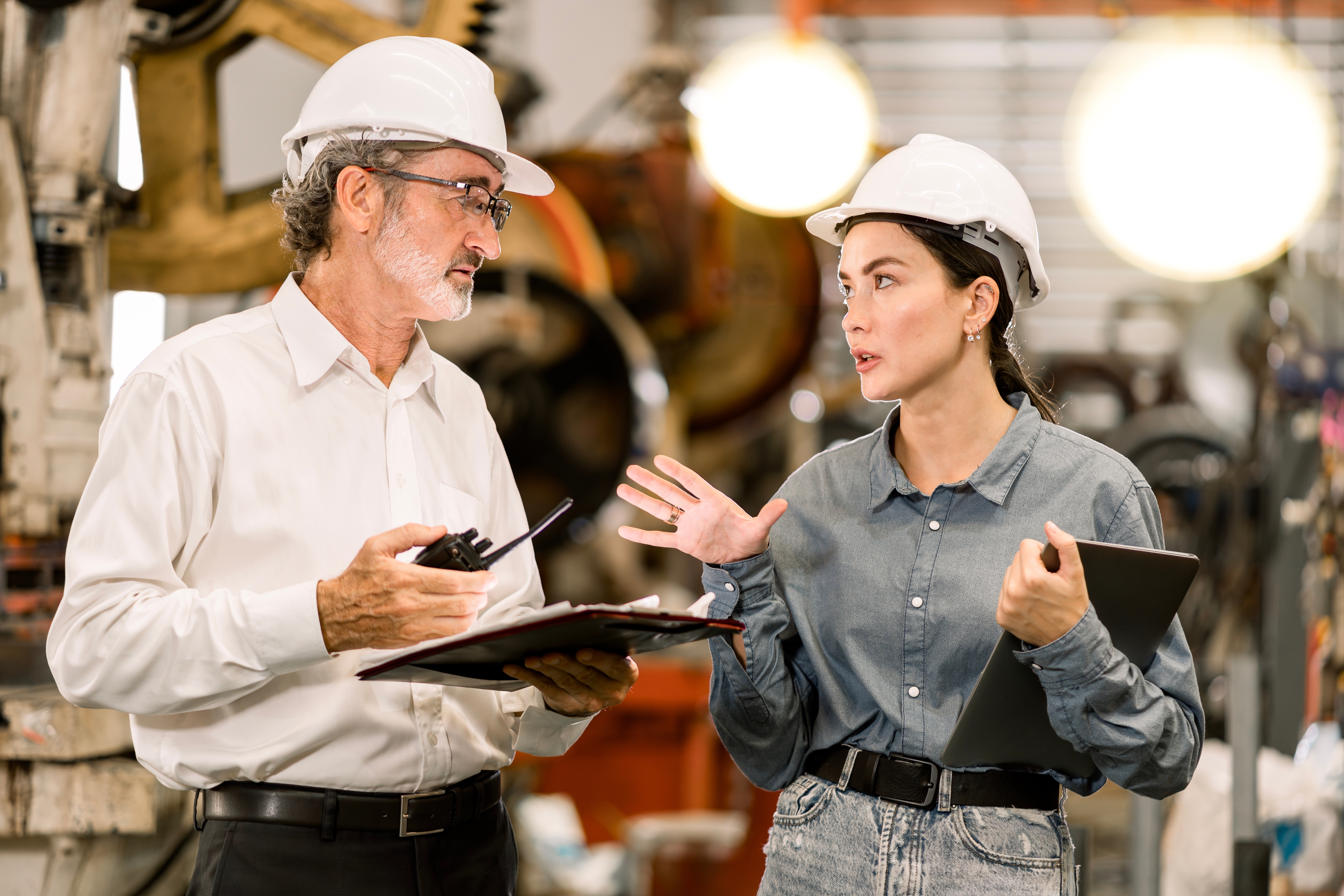 A man and woman wearing hard hats talk together in an industrial worksite. The man is holding a clipboard and walkie-talkie while the woman gestures with one hand and holds a tablet in the other. The header copy reads, “Voice and collaboration services. Better ways to work together.”