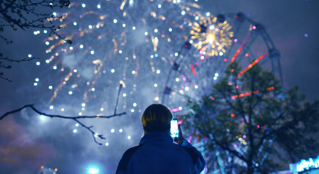 Man taking photo of Fourth of July fireworks with smartphone app