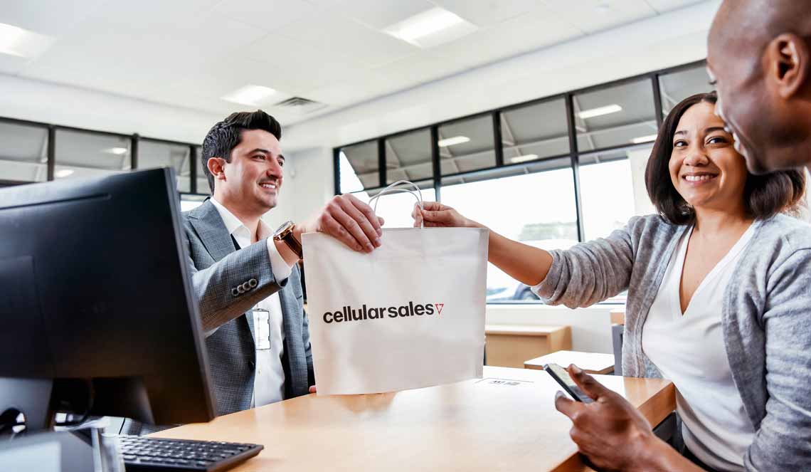 Cellular Sales wireless consultant handing a bag over to happy customers