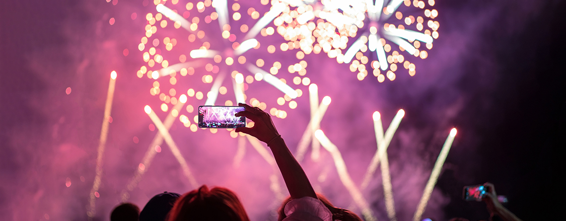 person holding up their phone to take pictures of fireworks on the 4th of July