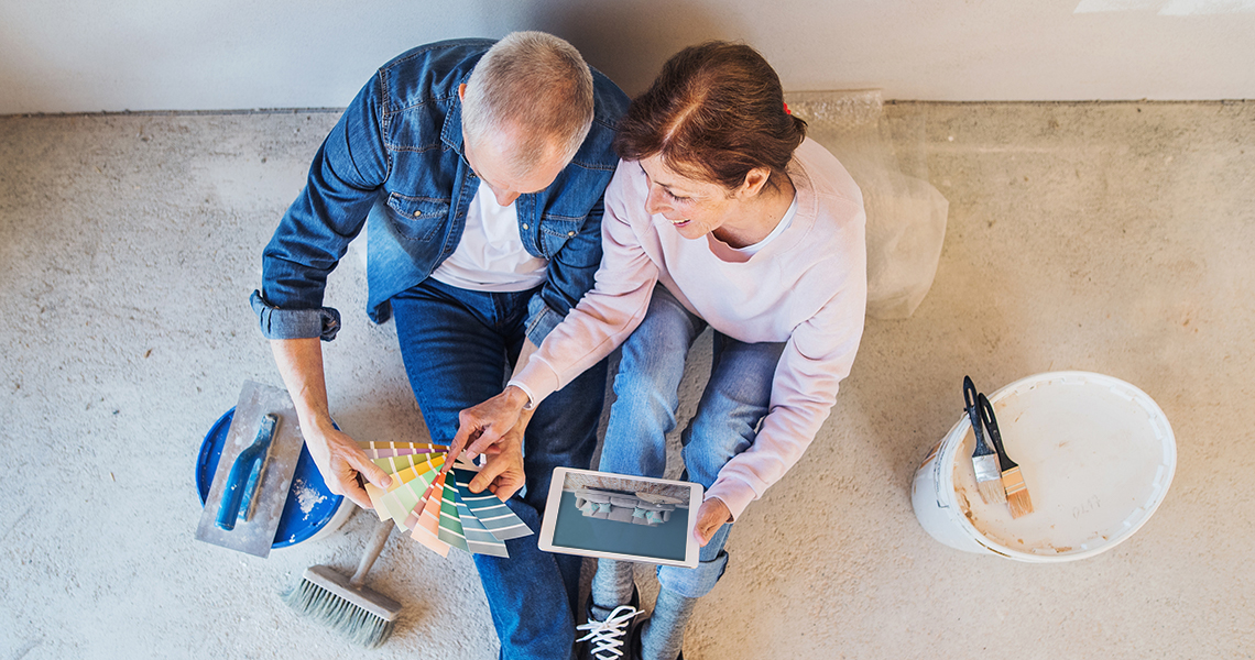 Couple sitting on floor looking over paint swatches while holding a Verizon tablet