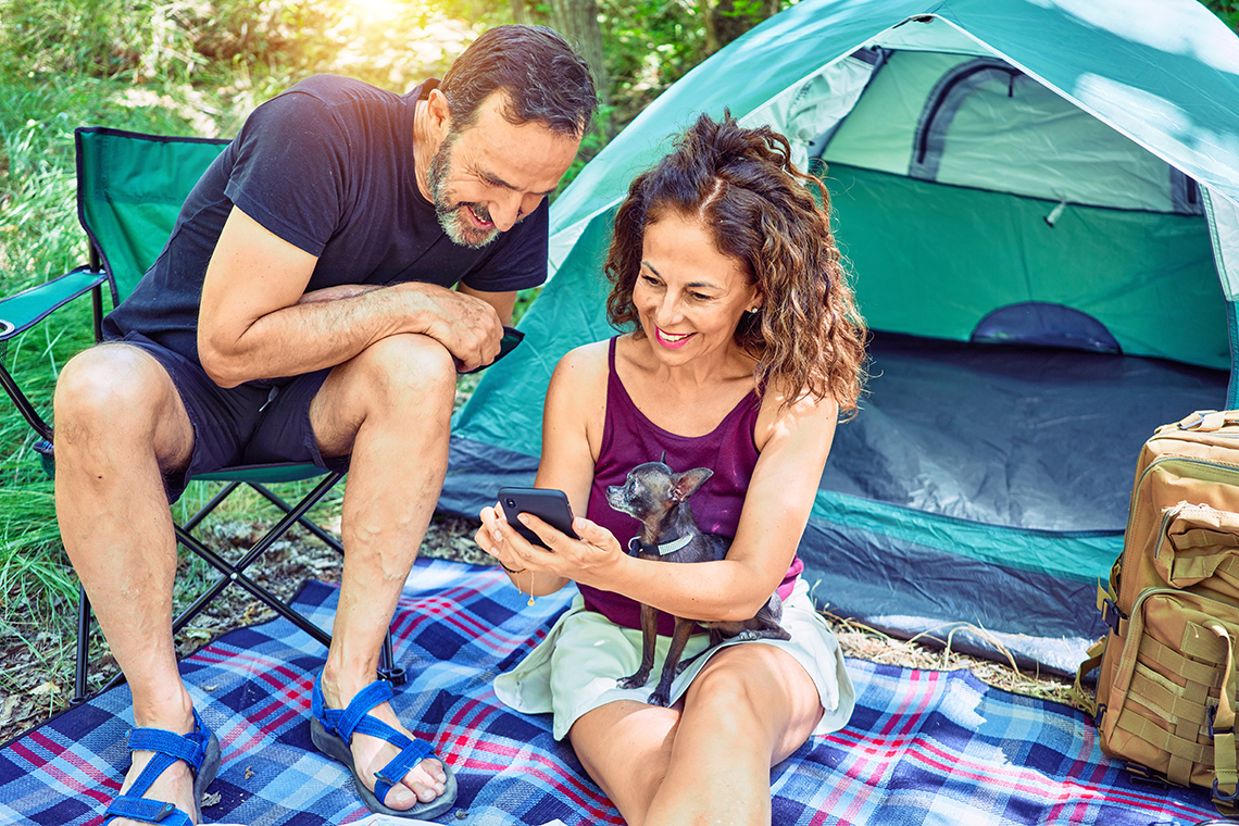 Couple looking at smartphone while camping in forest