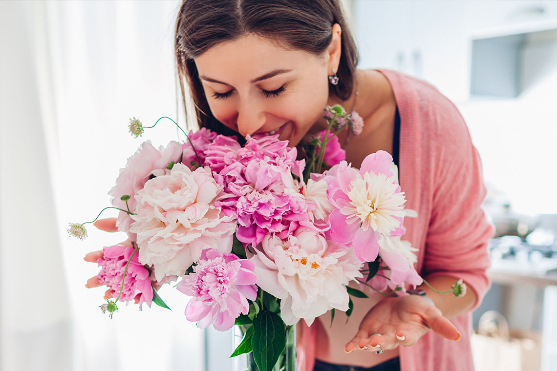 mom smelling pink flowers she received for Mother's Day