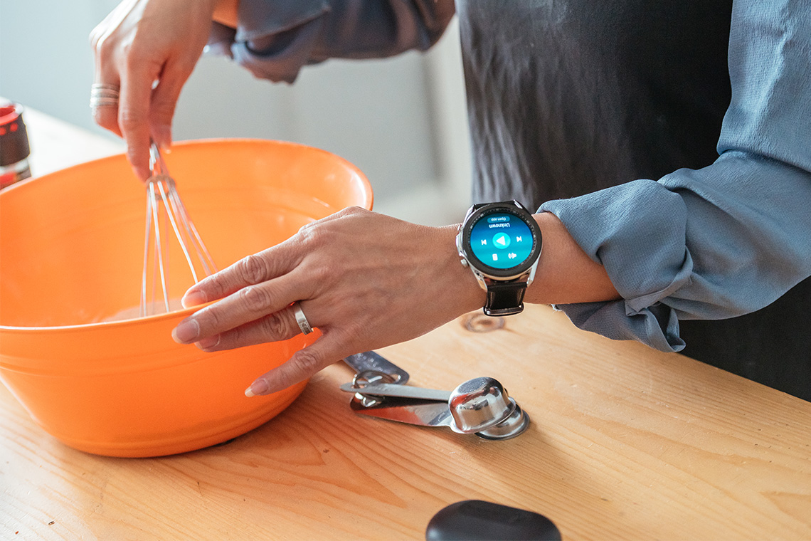 Mom using mixing bowl while wearing Samsung Galaxy smartwatch and JBL Tune 220 Earbuds
