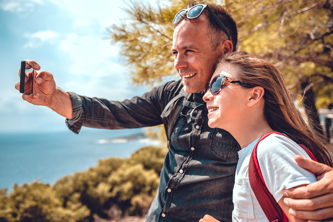 Dad and daughter taking selfie with smartphone while hiking