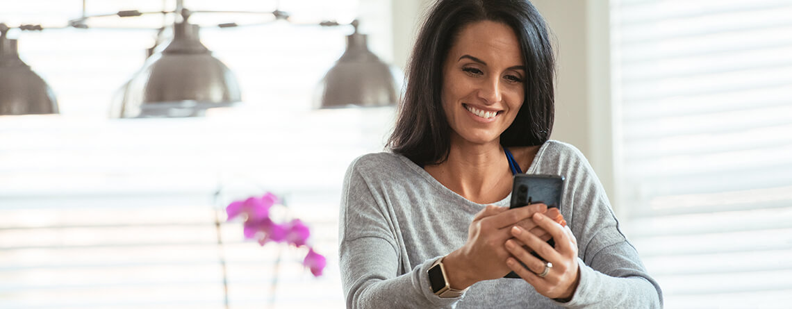 woman looking at smartphone in kitchen