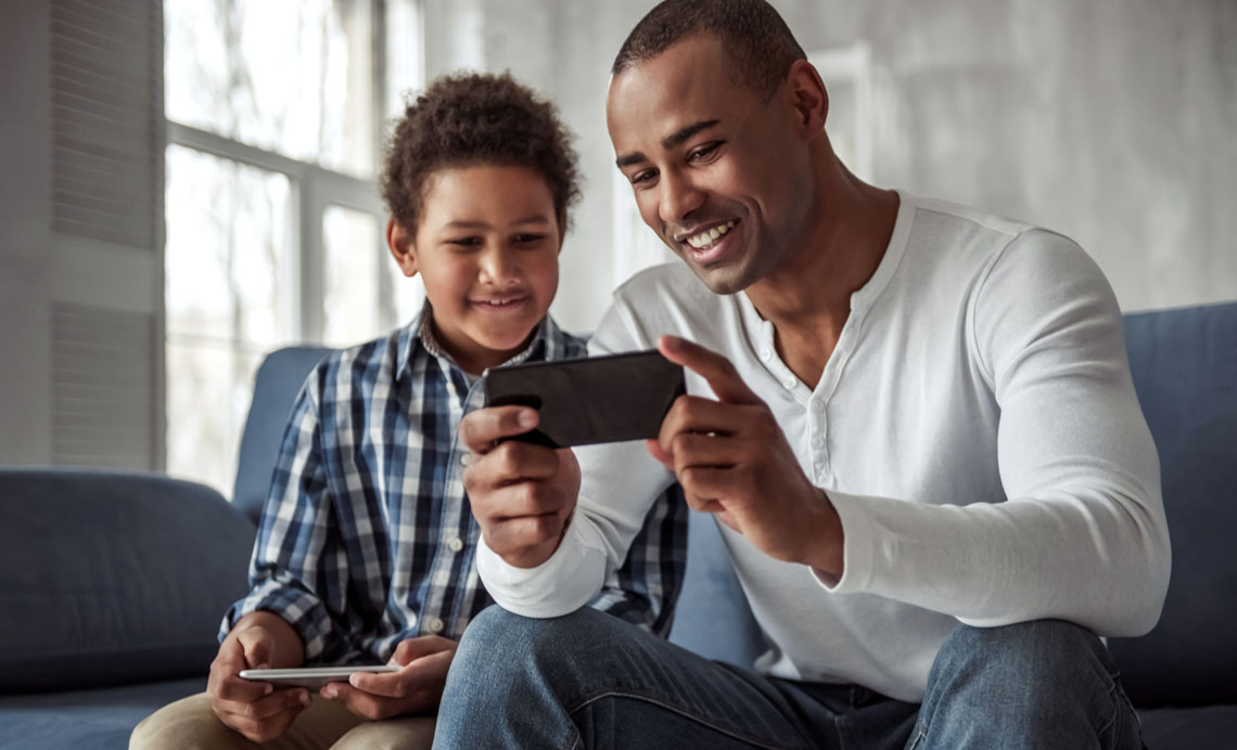 father and son looking at smartphone at home