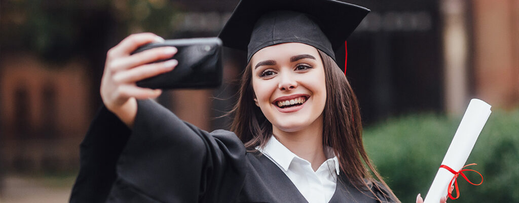 Female graduate taking selfie with smartphone