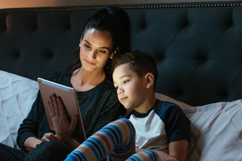 Mother and son watching movie on tablet in bed