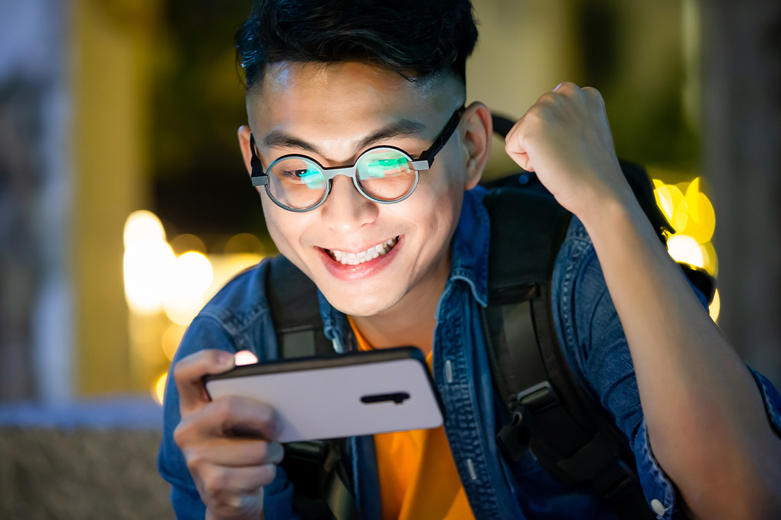 high school grad playing game on smartphone