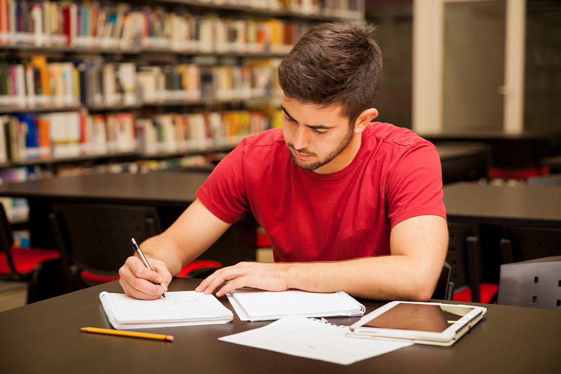 male student taking notes