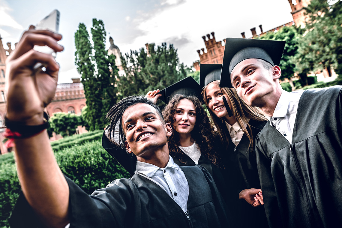 group of graduates taking selfie with smartphone