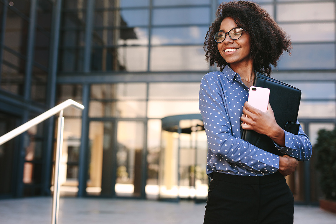 female graduate walking outside office building