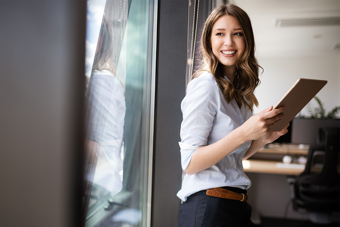 young female graduate holding tablet while smiling