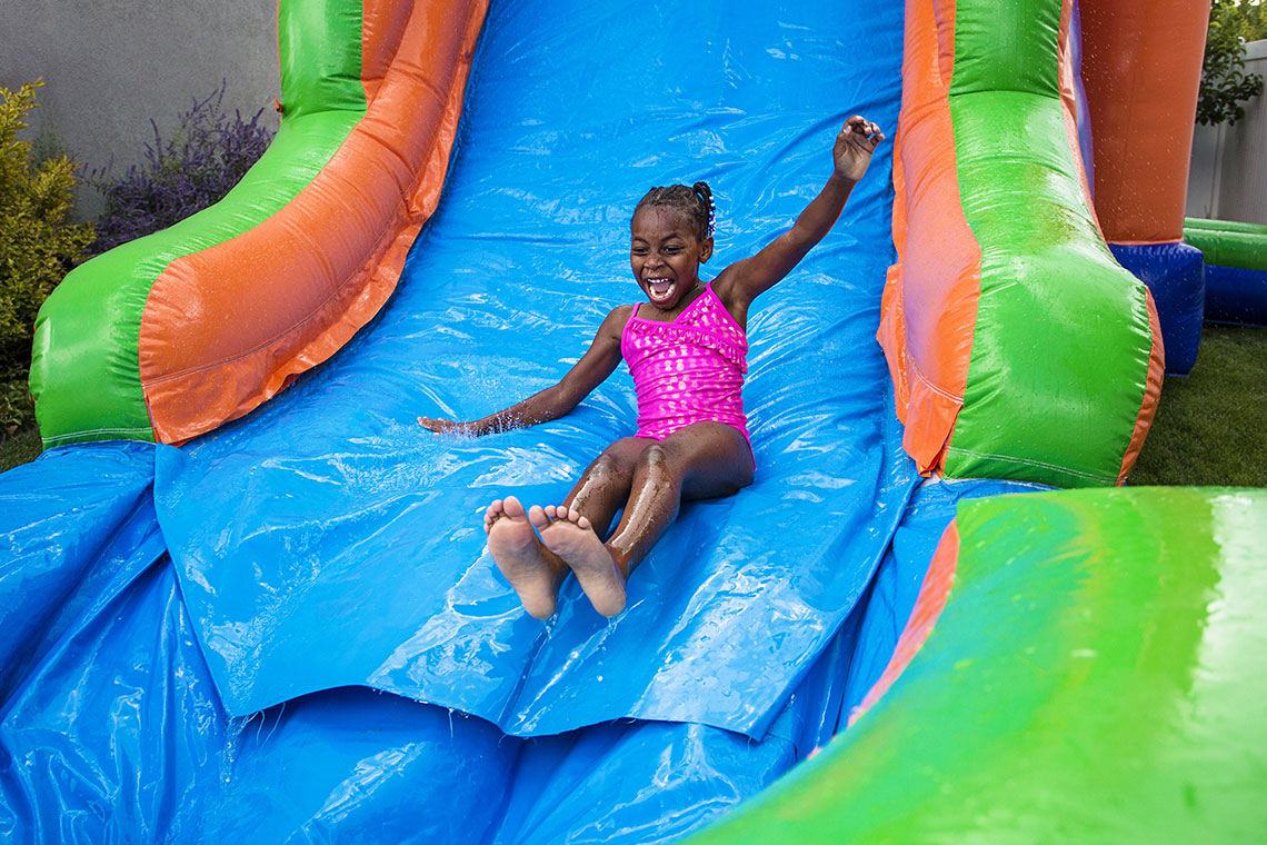 girl in pink bathing suit sliding down slipnslide