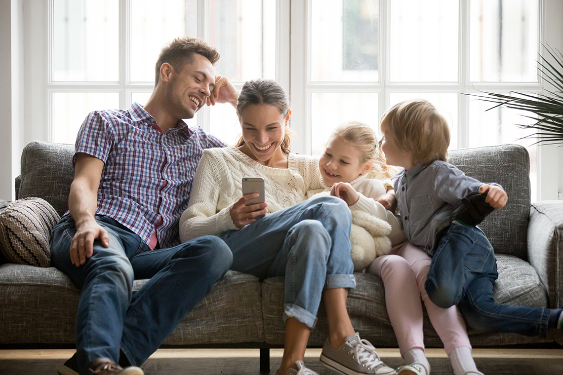 family sitting on couch looking at smartphone