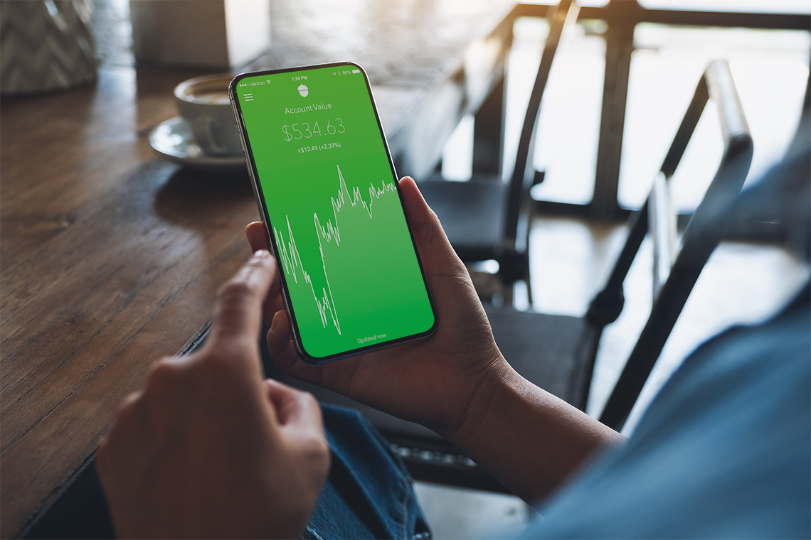 person checking Acorns app on Apple iPhone