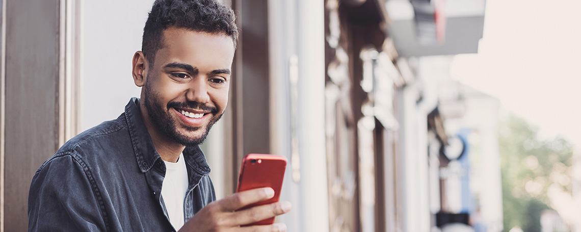 man checking passive income on red smartphone outside