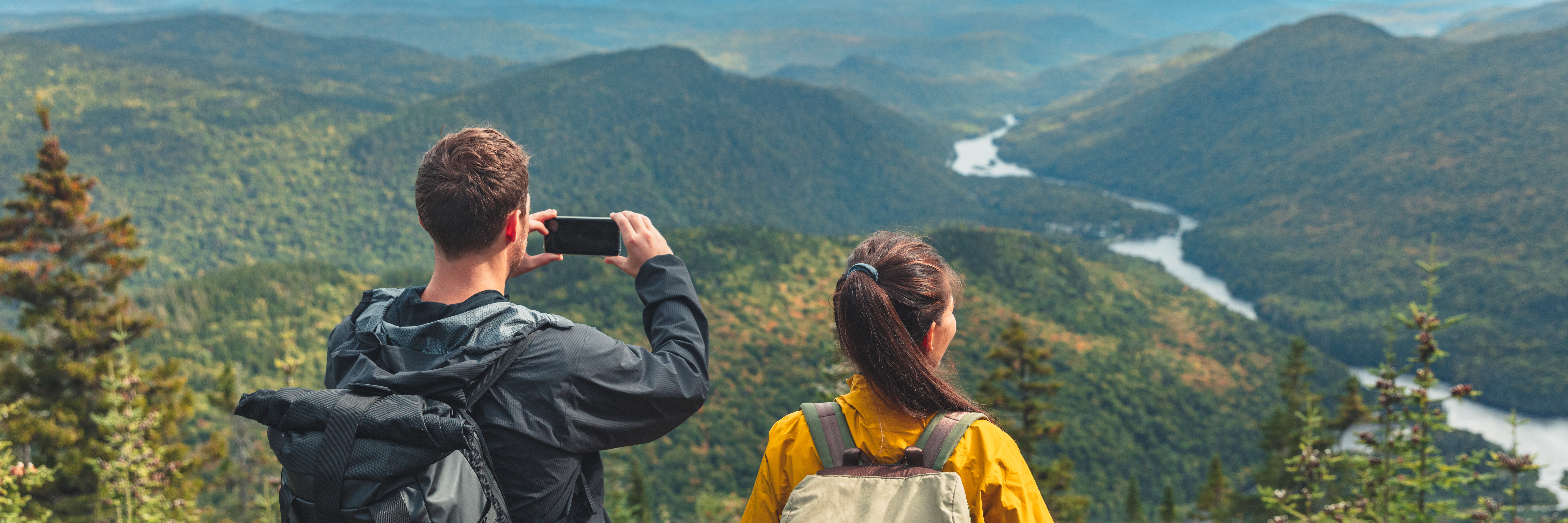 two hikers taking picture with smartphone on top of mountain