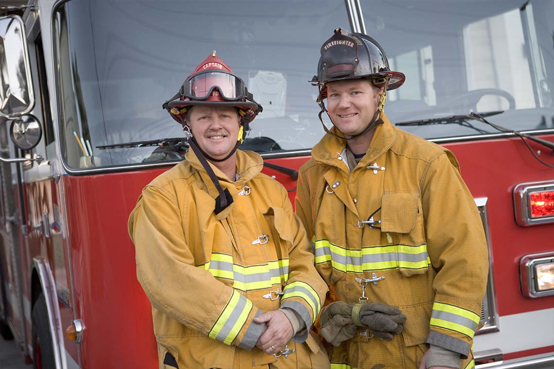 two firefighters standing in front of firetruck