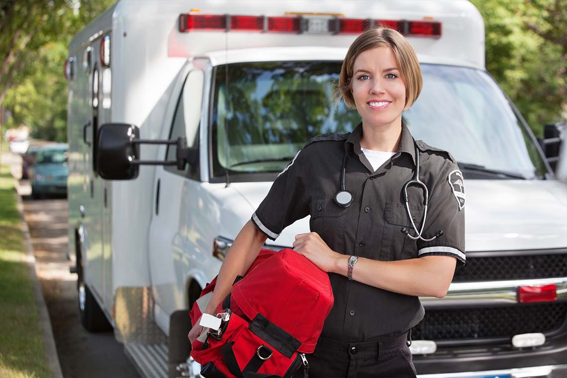 emt with red bag standing in front of ambulace
