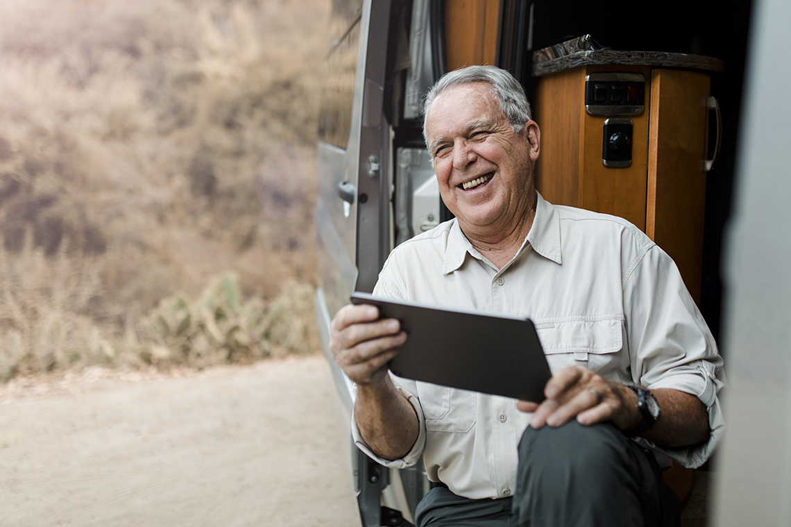 senior man using hotspot to check tablet in camper
