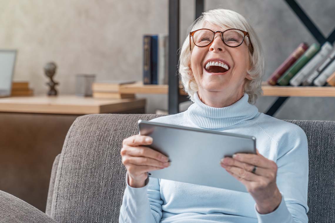 senior woman laughing while holding Apple iPad