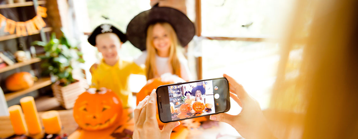 mother taking pictures of her children in halloween costumes