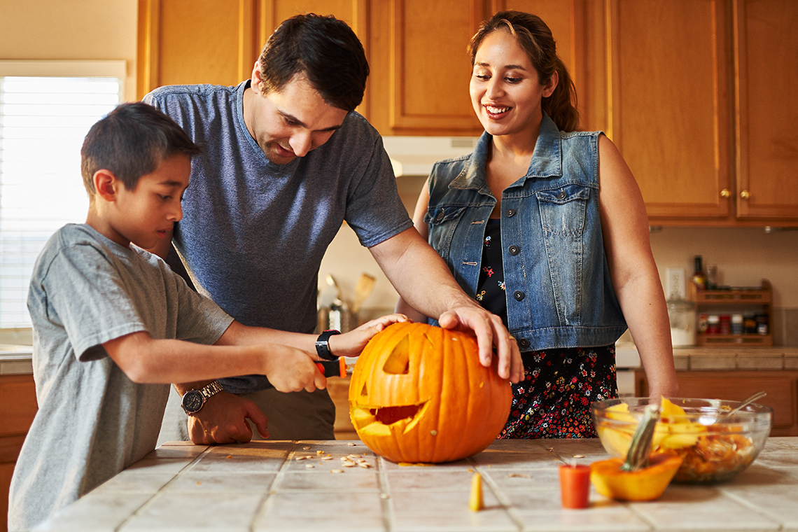 family carving pumpkins in kitchen for Halloween 2021