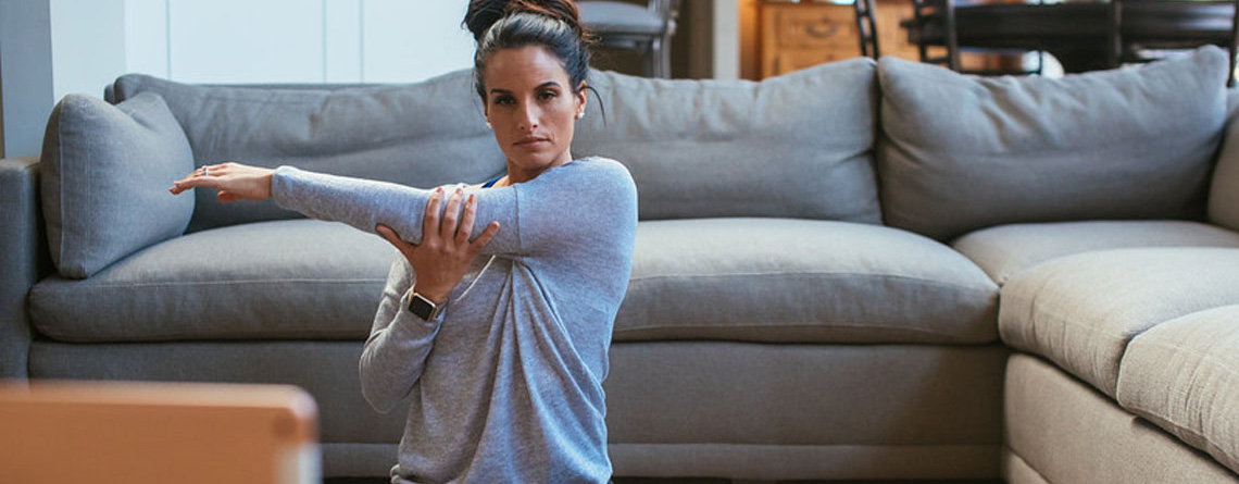 woman doing yoga in living room using Apple iPad and Apple Watch