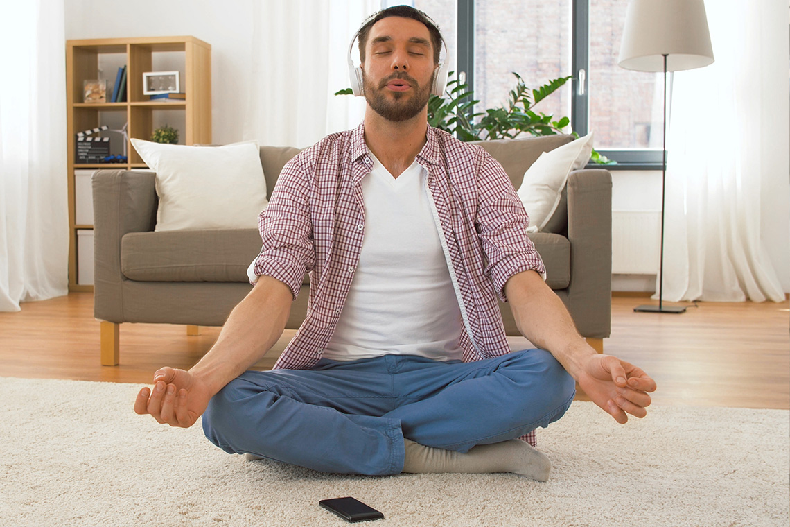 man meditating on floor with headphones on