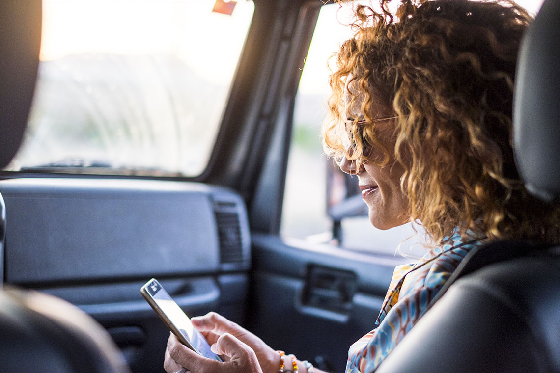 woman checking smartphone in car