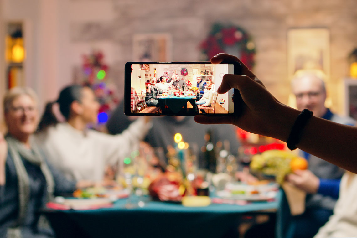 someone taking photo of family at diner table with smartphone