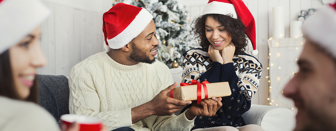 couple exchanging gifts with santa hats on