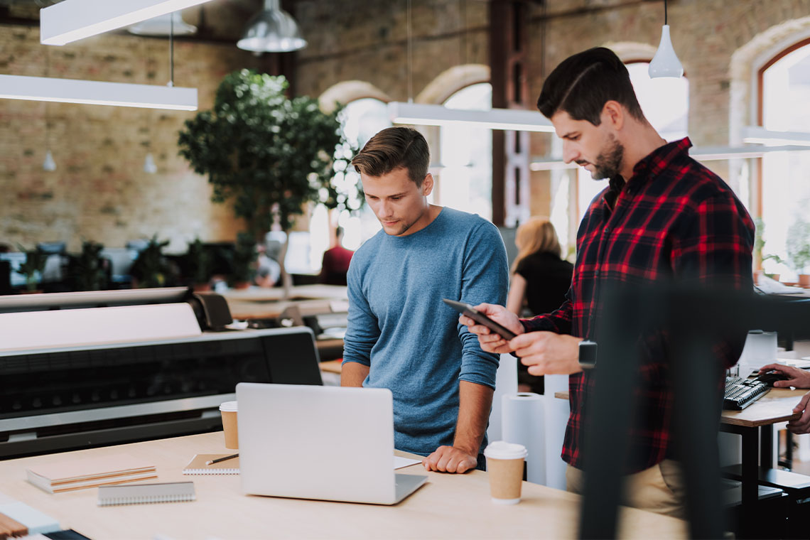 2 coworkers at office checking emails on smartphone