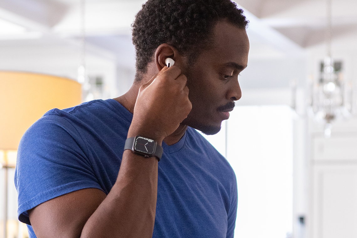 man putting in Apple AirPods while wearing Apple Smartwatch