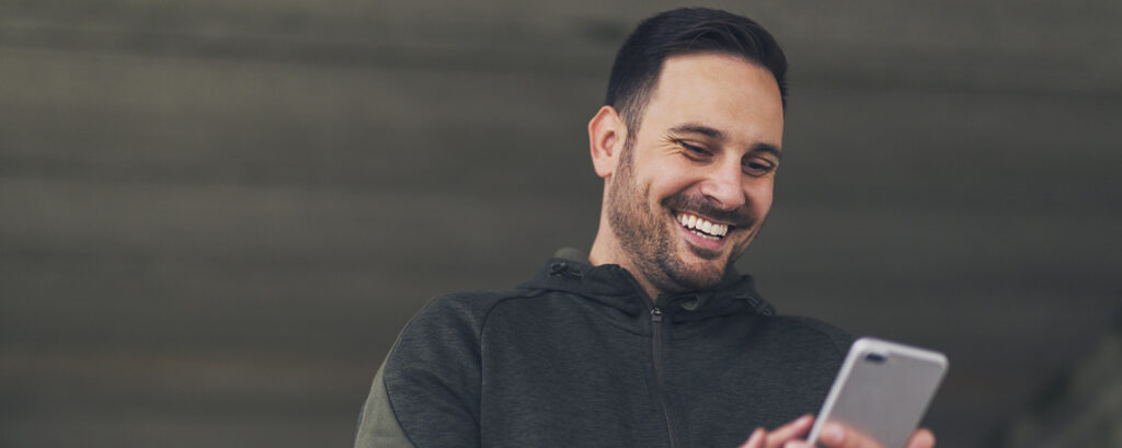 man smiling while checking new smartphone