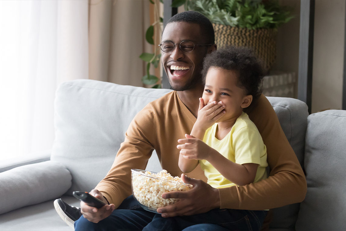 father and son watching movie inside on a snowy day