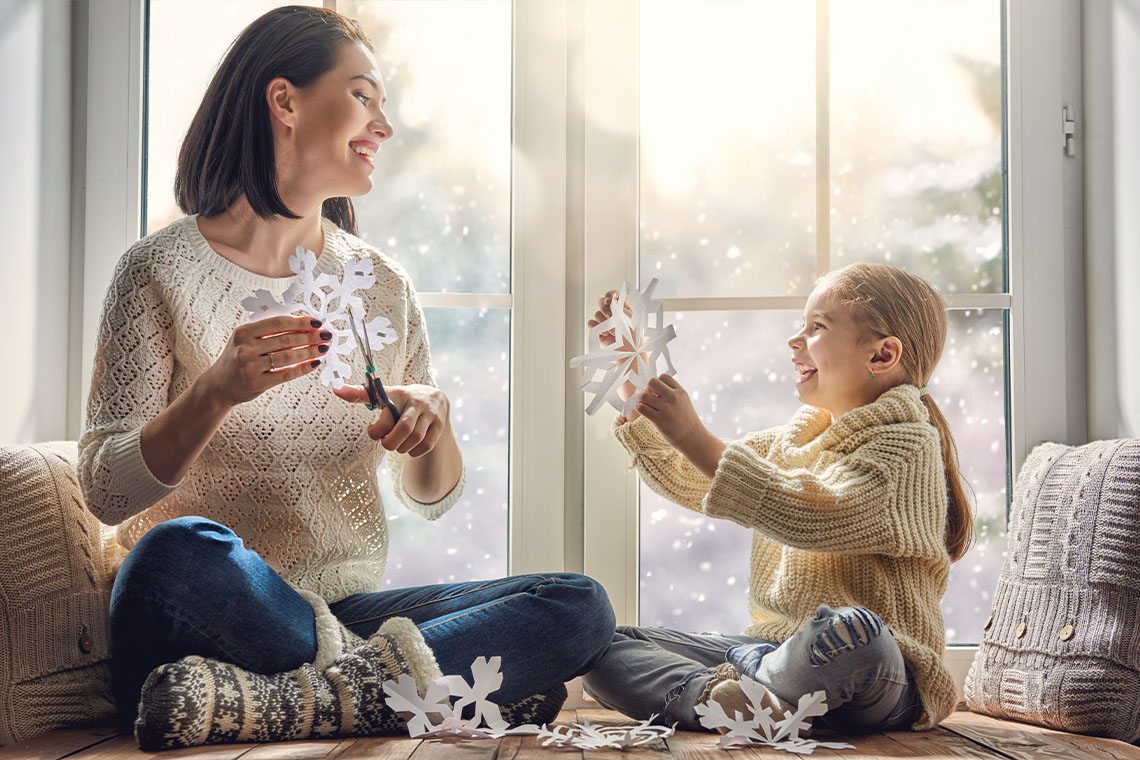 mother and daughter cutting out paper snowflakes