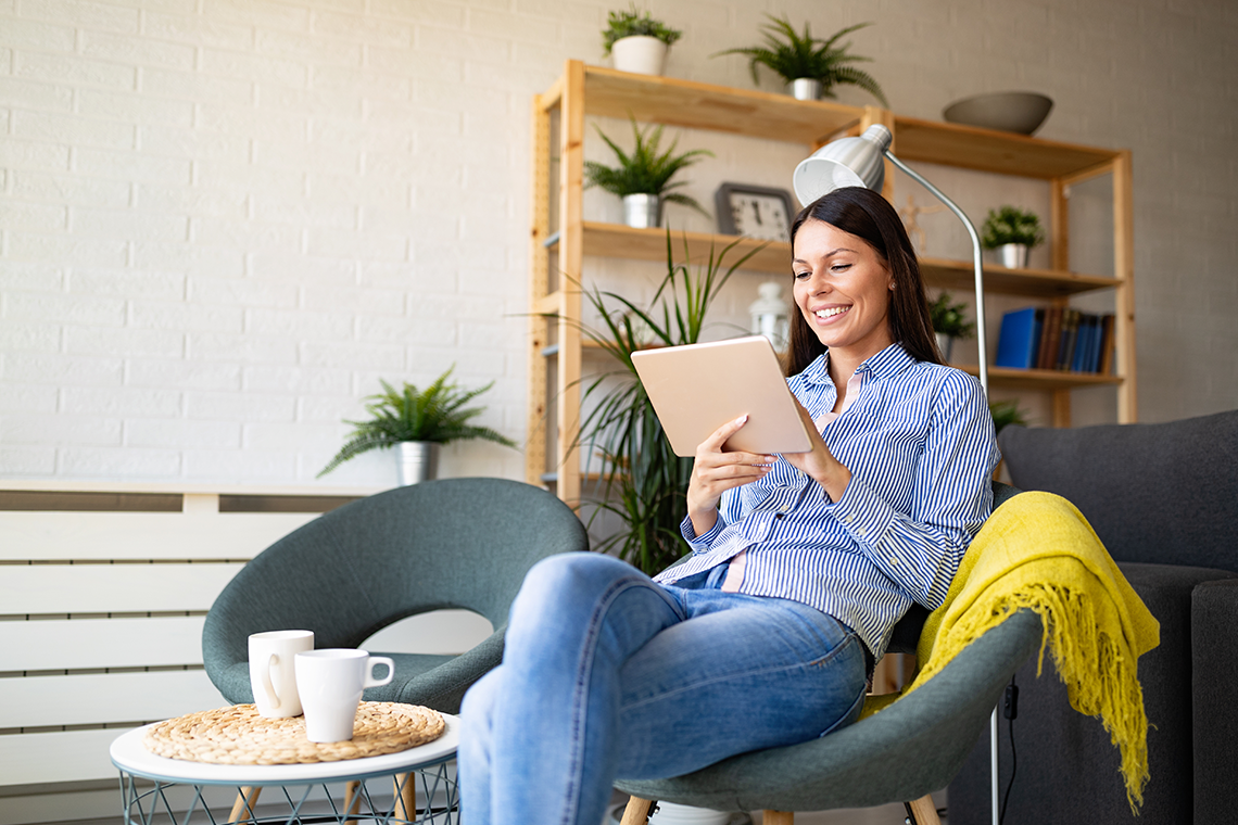 woman with reading on tablet in living room