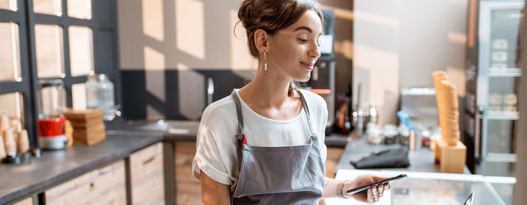 A woman looks at her phone at an ice cream counter.