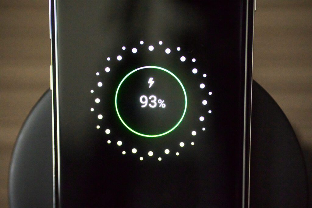 A phone sits on a wireless charger. The screen shows battery at 93 percent.