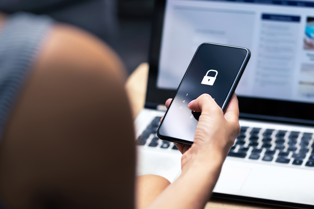 Over the shoulder shot of a person holding a smartphone with a padlock icon on screen.