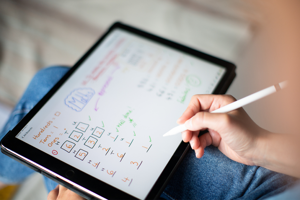 A person holds a stylus with a tablet in their lap, doing math lessons.