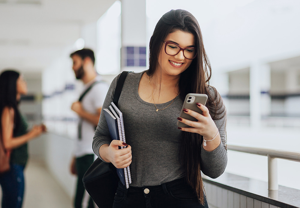 woman smiling at phone while walking outside