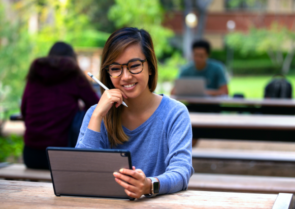 woman using tablet with stylus outside at picnic table