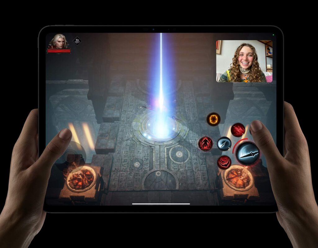 2024 iPad Pro against a black background, held two-handed, showing a bright gaming display. 