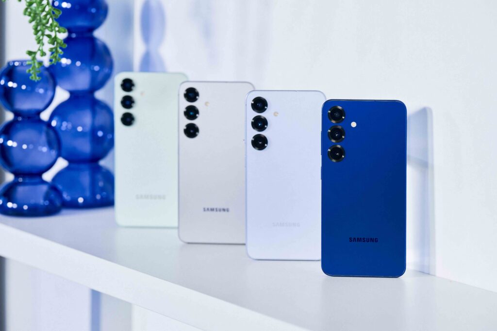 A group of Samsung Galaxy S25 smartphones, arranged standing diagonally on a white tabletop.
